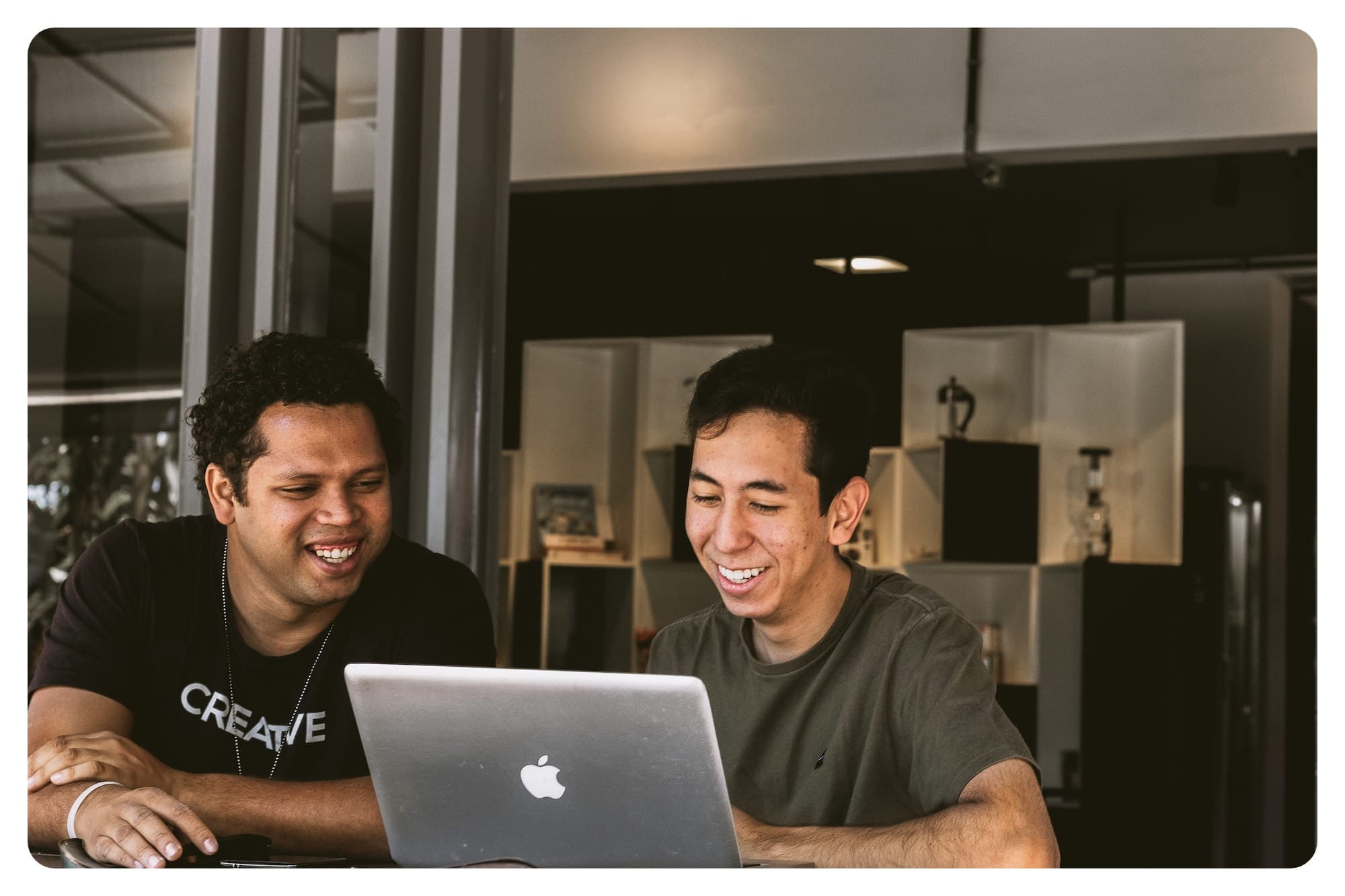 two smiling men looking at MacBook